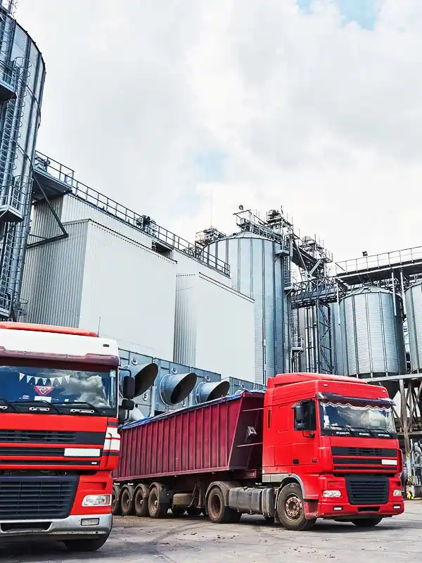 Deux camions de transport effectuent leur chargement devant une usine.