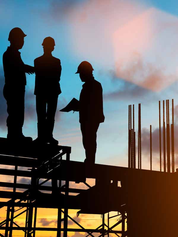 Ouvriers du bâtiment et des travaux publics échangent sur le toit d'une immeuble en chantier, sur fond de levée de soleil.